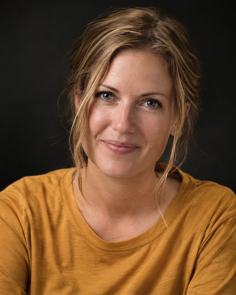 Lena Krüger, sandblondes Haar, ockerfarbenes Hemd ohne Druck, dunkles Studio